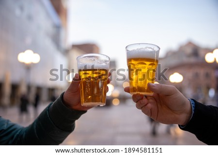 Closeup of two hands clinking beer stein glasses.