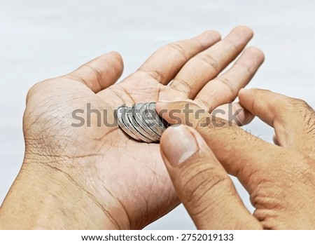 Close-up of two hands holding stack of silver coins on white background