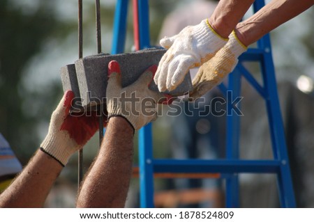 A closeup of two hands passing bricks at contruction site