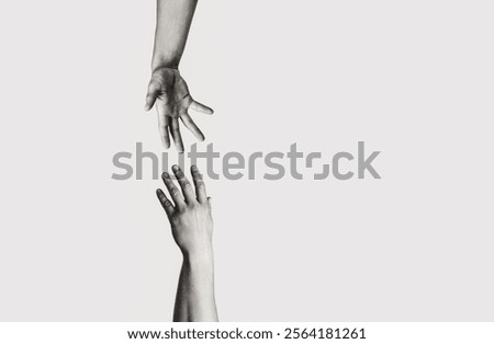 Closeup two hands reaching to each other. Concept for salvation, rescue, friendship, guidance, help, helping. Black and white.