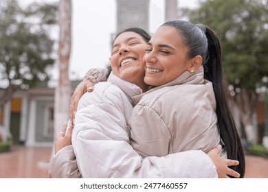 Close-up of two latin female friends embracing energetically in the city in winter - Powered by Shutterstock