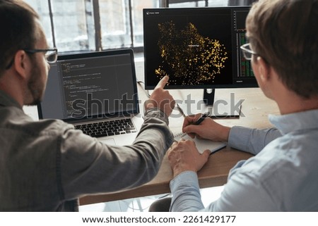 Closeup of two men data science specialists working at office together, analyzing big data on screen. Coders working on new project 