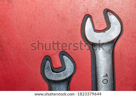 Close-up of two old chrome wrenches on red background.