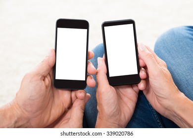 Close-up Of Two People Hands Holding Blank Display Mobile Phones