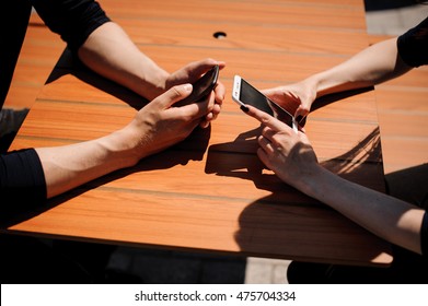 Close-up Of Two People Hands With Mobile Phones