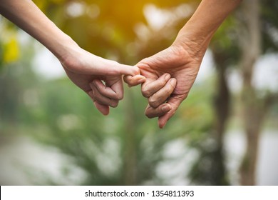 Closeup two person hook each other's little finger on nature background. - Powered by Shutterstock