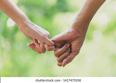 Closeup two person hook each other's little finger on nature background. - Powered by Shutterstock