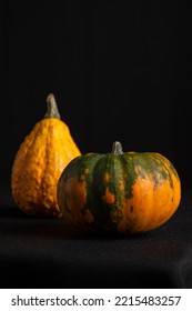 Close-up Two Pumpkins For Halloween On Table With Tablecloth And Black Background, Selective Focus, Vertical, With Copy Space