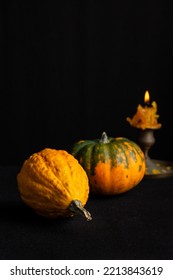 Close-up Of Two Pumpkins And Lit Candle, Selective Focus, On Tablecloth And Black Background, Vertical, With Copy Space