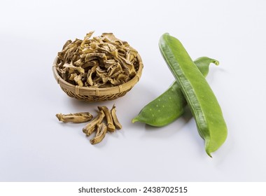 Close-up of two raw sword beans with dried pieces on bamboo basket and white floor, South Korea
