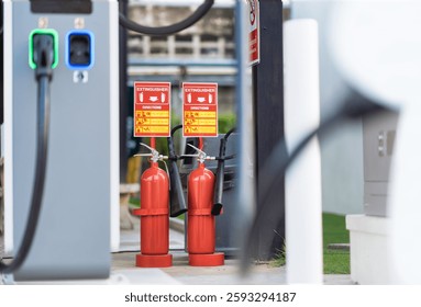 A close-up of two red fire extinguishers at an EV charging station with safety instructions above, ensuring emergency preparedness and highlighting fire safety measures in modern electric vehicle infr