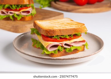 Close-up of two sandwiches with bacon, salami, prosciutto and fresh vegetables on rustic wooden cutting board. Club sandwich concept - Powered by Shutterstock