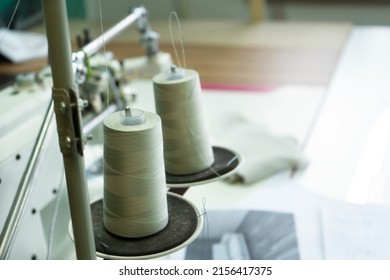 Close-up of a two spools of thread on the industrial sewing machine. A seamstress workplace with a ruller and spool of threads.