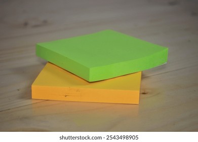 Close-up of two sticky note pads, one green and one yellow, stacked on a wooden surface - Powered by Shutterstock