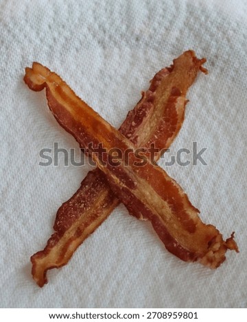 close-up of two strips of crisp cooked bacon arranged in an 