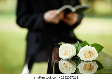 Closeup of two white roses on coffin at outdoor funeral ceremony, copy space