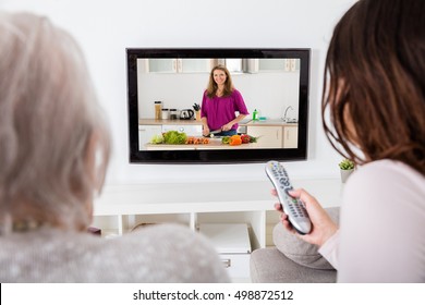 Close-up Of Two Women Watching Cooking Show On Television At Home