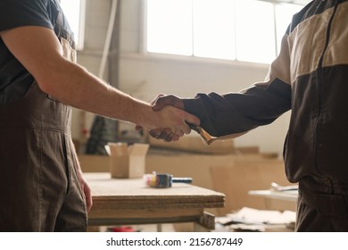 Close-up of two workers shaking hands and greeting each other before the beginning of work at factory - Powered by Shutterstock