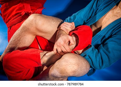 Close-up two wrestlers of grappling and jiu jitsu in a blue and red kimono makes armlock. Wrestler submission wrestling  blue tatami