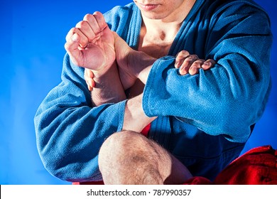 Close-up two wrestlers of grappling and jiu jitsu in a blue and red kimono makes armbar .Submission wrestling   on blue tatami
