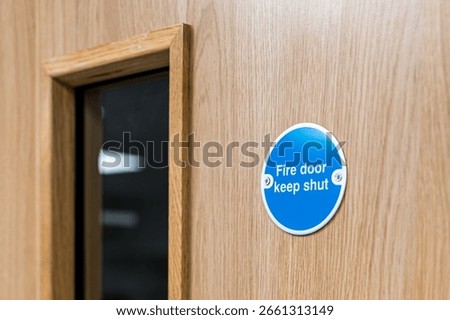 Close-up of a typical Fire Door Keep Shut sign seen on an interior door within a British hospital.