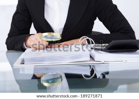 Closeup of uditor scrutinizing financial documents at desk in office