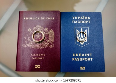 Nahaufnahme des ukrainischen und chilenischen Reisepasses mit Hochzeitsringen

