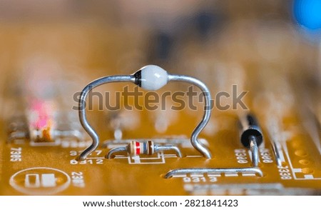 Closeup ultrafast avalanche rectifier diode and color coded resistor on beige PCB. High mounted two-terminal electronic component on orange blur background of printed circuit board. Through-hole tech.