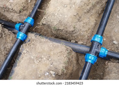Close-up Of Underground Irrigation System, Plumbing Water Drainage Installation. Elbow Fitting And Pvc Pipes At Bend In Dirt Trench Outdoors