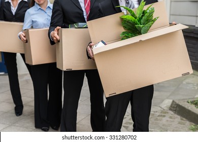 Close-up Of Unemployed Businesspeople Carrying Cardboard Boxes - Powered by Shutterstock