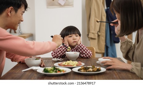 Closeup Of Unhappy Asian Preschool Boy Shaking Head And Saying No To Eat At Dining Table To His Mom And Dad At Home