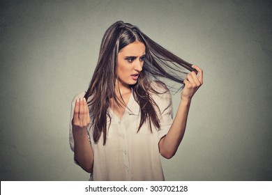Closeup unhappy frustrated young woman surprised she is losing hair, receding hairline. Gray background. Human face expression emotion. Beauty hairstyle concept 