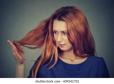 Closeup unhappy upset frustrated young woman surprised she is losing hair, noticed split ends receding hairline. Gray background. Human face expression emotion. Beauty hairstyle concept