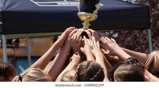 Close-up of unidentified teenage girls soccer players' hands holding up a trophy after winning a tournament. - Powered by Shutterstock