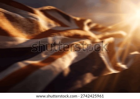 Close-up of the Union Jack flag waving dynamically, illuminated by warm, golden sun rays creating a lens flare effect.