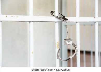 Closeup of unlocked handcuffs hanging on jail bars
