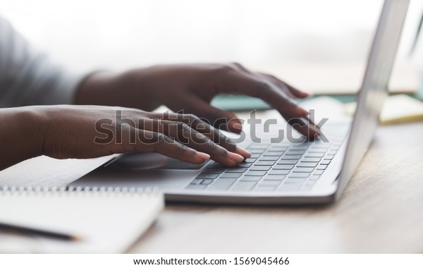 Closeup of unrecognizable\
afro woman typing on laptop keyboard while working in office,\
panorama