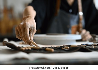 Close-up of unrecognizable artist's hands picking a work tool, doing a sculpture from clay. - Powered by Shutterstock