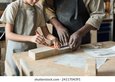 Closeup of unrecognizable carpenter teaching little girl woodworking in crafts school for children - Powered by Shutterstock