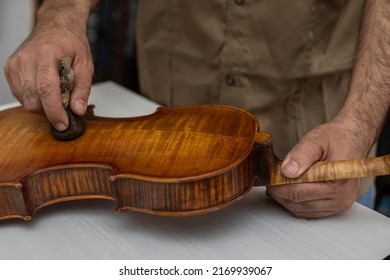 Close-up of unrecognizable Latin American Luthier varnishes a violin the old fashioned way using natural dyes. Concept stringed instruments