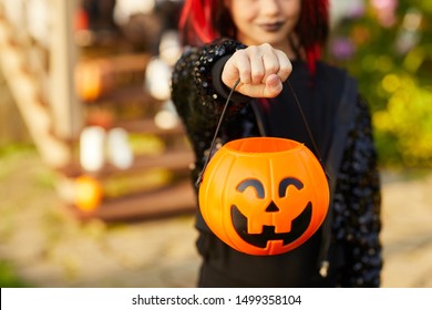 Closeup of unrecognizable little girl wearing Halloween costume and holding pumpkin basket in trick or treat season, copy space - Shutterstock ID 1499358104