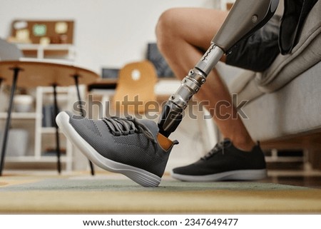 Closeup of unrecognizable man with bionic prosthetic leg at home indoors, copy space