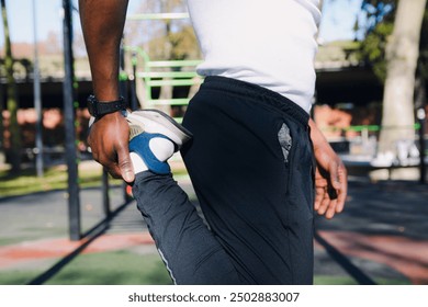 Close-up of unrecognizable Man doing correct quadriceps femoris stretch during sports warm-up, side view of man holding his fist against gluteus warming up and stretching before training - Powered by Shutterstock