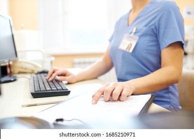 Close-up Of Unrecognizable Nurse Sitting At Desk And Using Computer While Analyzing Medical Notes