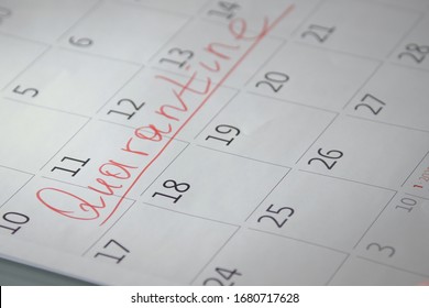 Close-up of unrecognizable person writes Quarantine with a red felt-tip pen on a calendar. Quarantine compliance. Calendar showing nothing to do except quarantine when pandemic covid-19 is raging