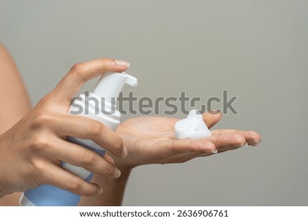 Close-up of unrecognizable person's hands using a pump mechanism to get a dollop of white, airy cosmetic lather. Concept of daily sanitation, personal treatment, or bodycare ritual.