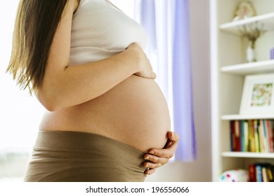 Close-up of unrecognizable pregnant woman with hands over tummy