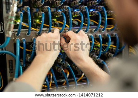 Close-up of unrecognizable server support specialist checking cables of switchboard while examining server, copy space
