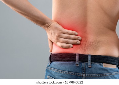 Closeup Of Unrecognizable Topless Man Touching His Loin Zone Highlighted With Red, Suffering From Chronic Or Acute Kidney Disease, Grey Studio Background, Copy Space. Healthcare Concept