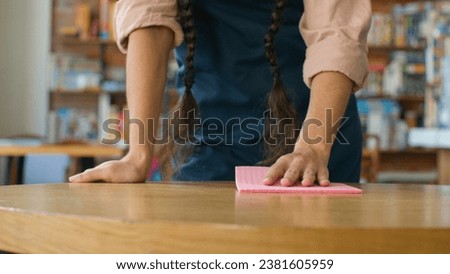 Close-up unrecognizable woman barista waitress in apron wipe table in cafe girl lady catering worker wiping cleaning restaurant clean prepare cafeteria for visitors treat surface from bacteria hygiene